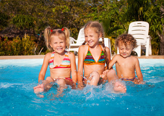 Wall Mural - two little girls and little boy playing in the pool