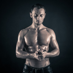 Wall Mural - Confident young man shirtless portrait against black background.