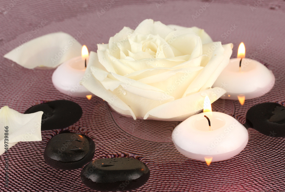 spa stones with flower and candles in water on plate