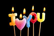 Burning candles making 'I love you' isolated on black