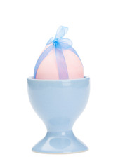 Wall Mural - Pink colored easter egg  with blue ribbon is in blue egg cup