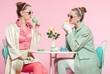 © ysbrandcosijn - Two girls blonde hair fifties fashion style drinking tea.