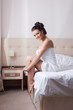 © Wisky - Smiling brunette sitting on hotel bed