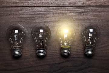 Wall Mural - bulb uniqueness concept on wooden background