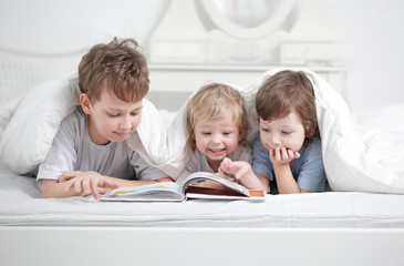 three boy read book indoors