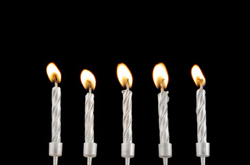 Five silver burning candles on black background