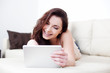 © baranq - Happy woman using her digital tablet on couch