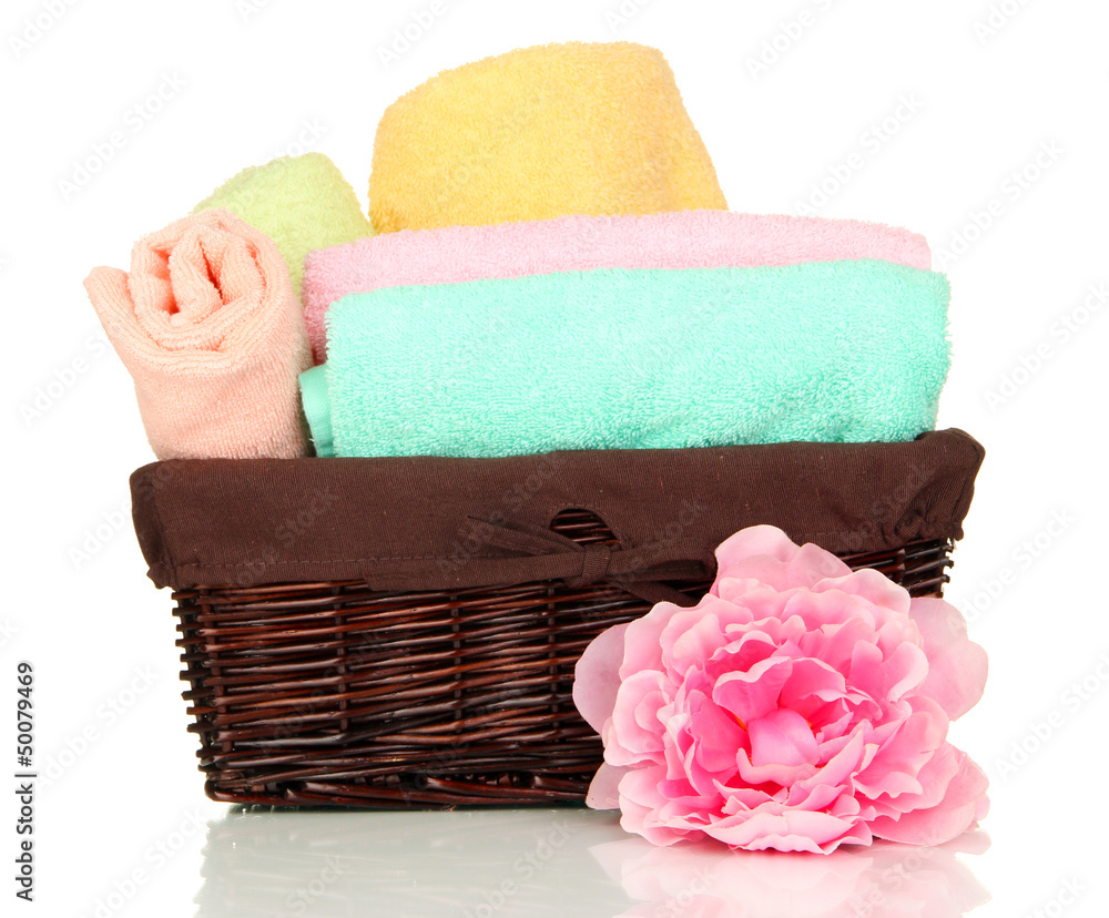 Bathroom towels folded in wicker basket isolated on white