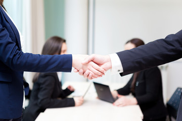 Business handshake at the office with bussiness people on backgr