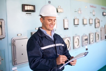 young smiling engineer taking notes at control room