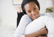 © JGI/Jamie Grill/Blend Images - Smiling Black woman laying in bed