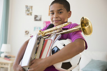 Hispanic Boy Carrying Trumpet, Books And Soccer Ball