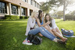 © Peathegee Inc/Blend Images - School friends sitting in grass looking at cell phone