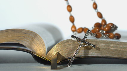 Sticker - Rosary beads falling on open bible on white background close up