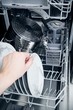 Hand takes plate from dishwasher