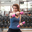 © pio3 - Young woman exercising with dumbbells in the gym.