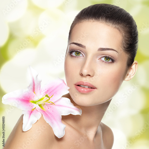 Nowoczesny obraz na płótnie Beauty face of young woman with flower. Beauty treatment concept