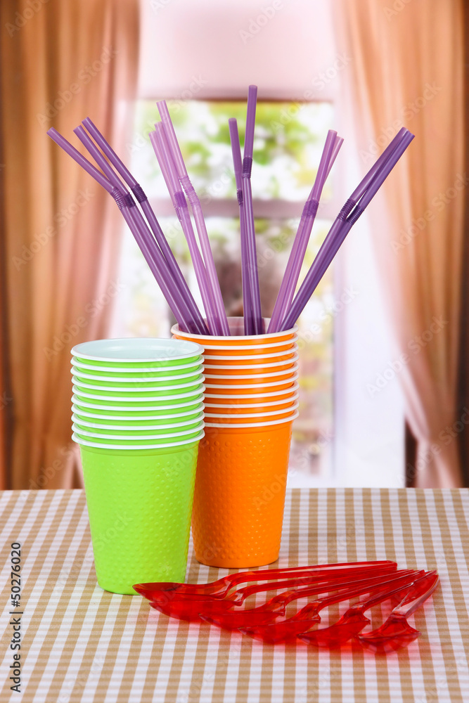 Plastic cups, spoons various colors on bright background