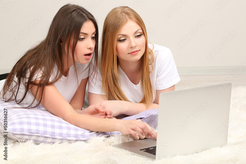 Two girl friends with with laptop on room