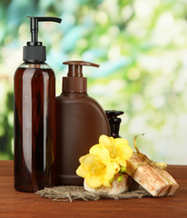 Liquid and hand-made soaps on wooden table, on green background