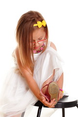 Wall Mural - Cute little girl white dress putting on her shoe