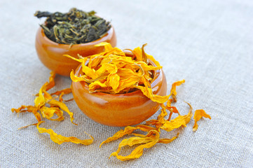 Dry healing herbs and petals in cups on sackcloth