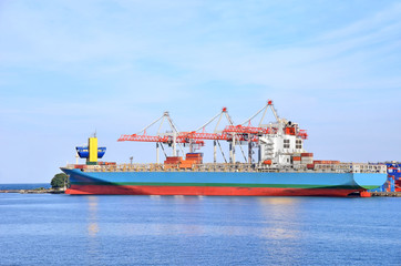 Container stack and ship under crane bridge