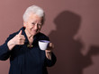 © vbaleha - Old woman enjoying coffee or tea cup over brown background