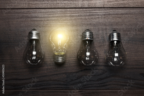 Fotografía glowing bulb uniqueness concept on wooden background