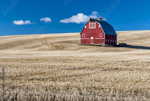 Fotografie, Obraz Red barn blue sky and wheat stuble field