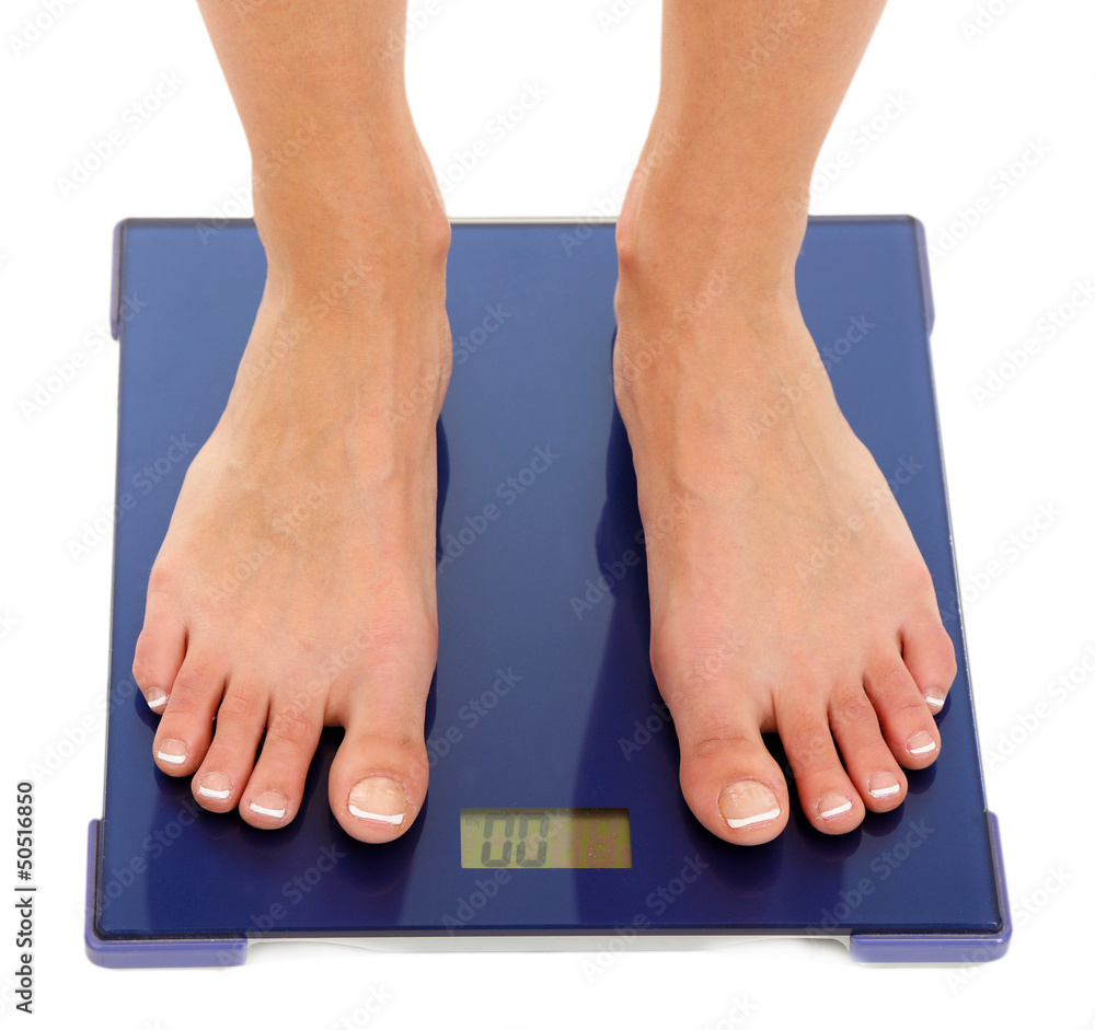 Bare female feet standing on scale isolated on white
