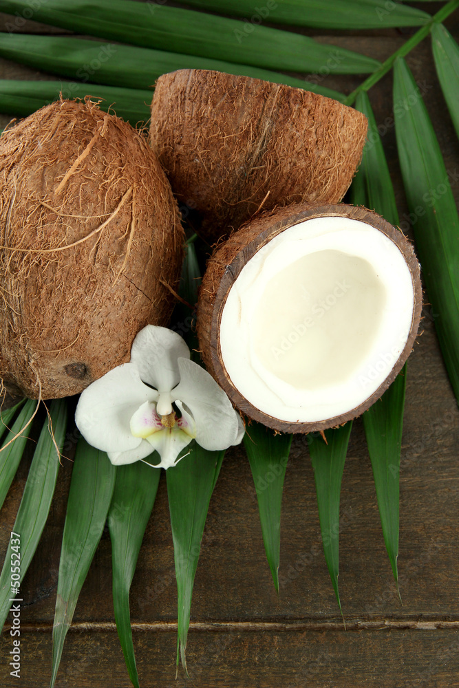 Coconuts with leaves and flower, on grey wooden background