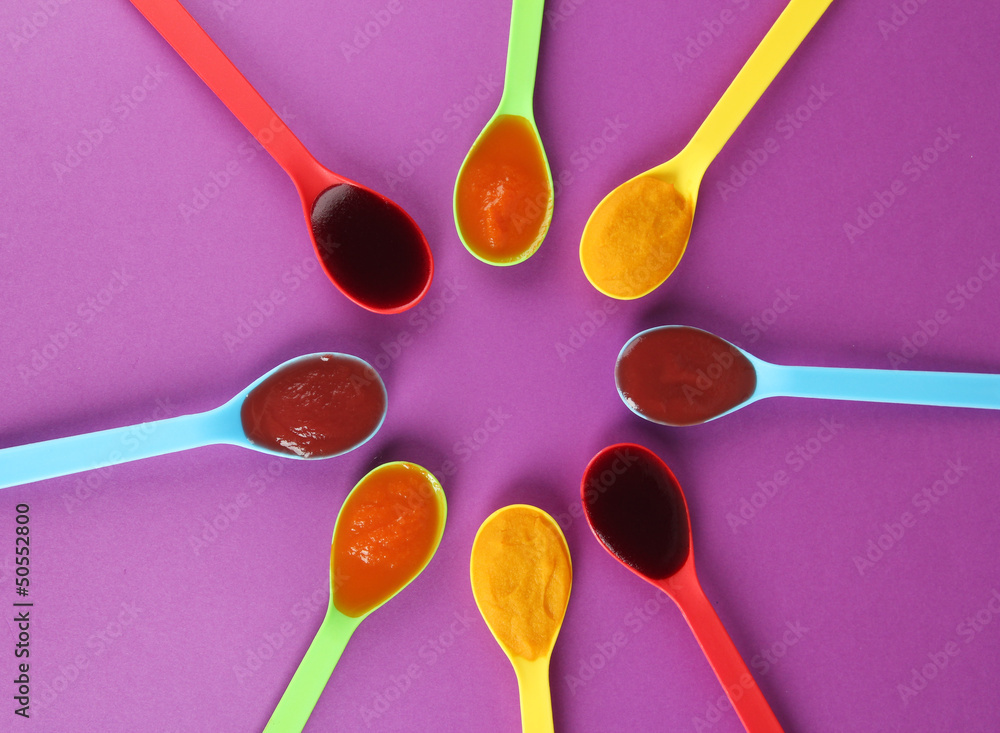 Baby puree in spoons on purple background