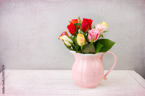 Fototapeta dla dzieci Roses flowers in pink jug on wooden vintage table