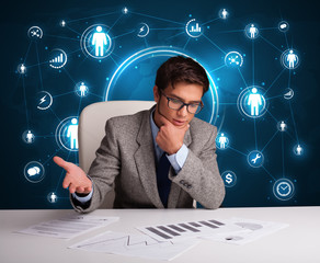 Businessman sitting at desk with social network icons