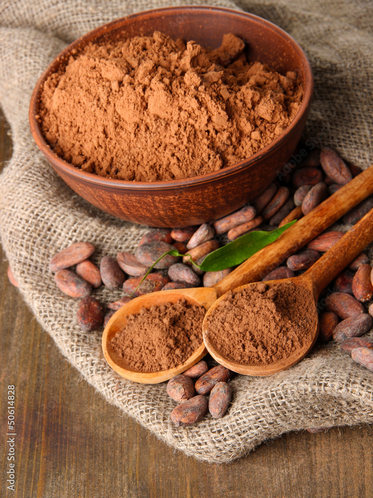 Cocoa powder and cocoa beans on wooden background