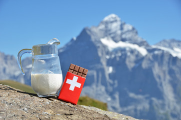 Wall Mural - Swiss chocolate and jug of milk against mountain peak. Switzerla