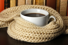 Cup Of Coffee Wrapped In Scarf On Books Background