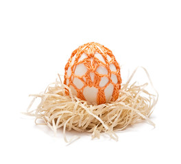 Easter egg  in a nest. Orange ornament is knitted