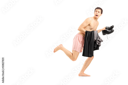 An embarrassed naked man in underwear holding his clothes and ru Stock-Foto | Adobe Stock
