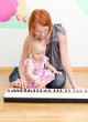 Little girl and her mother playing the piano
