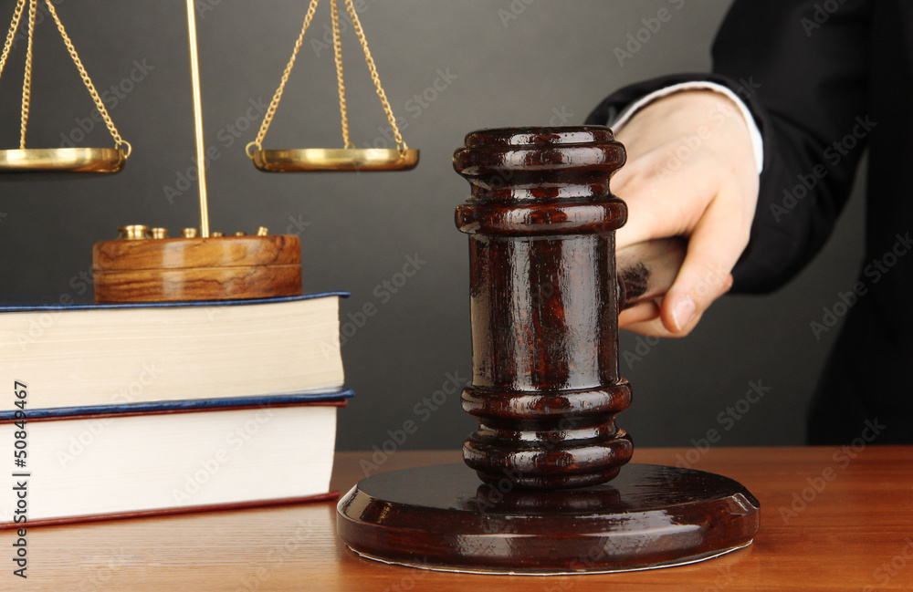 Judge's gavel in hand on grey background