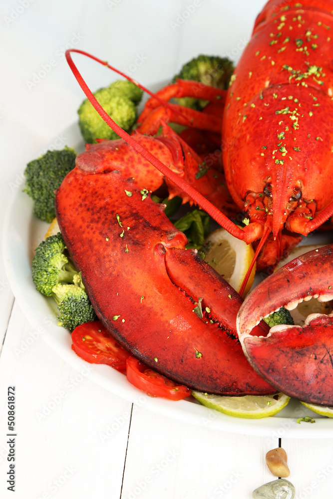 Red lobster on platter with vegetables on wooden table close-up