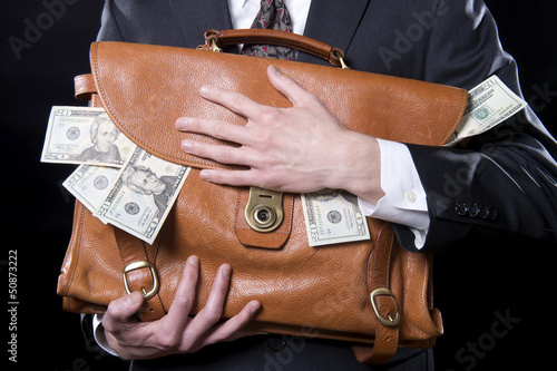 Fotomural Closeup of man holding briefcase with money spilling out