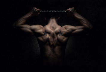 Wall Mural - Muscular sports man stretching out over dark background