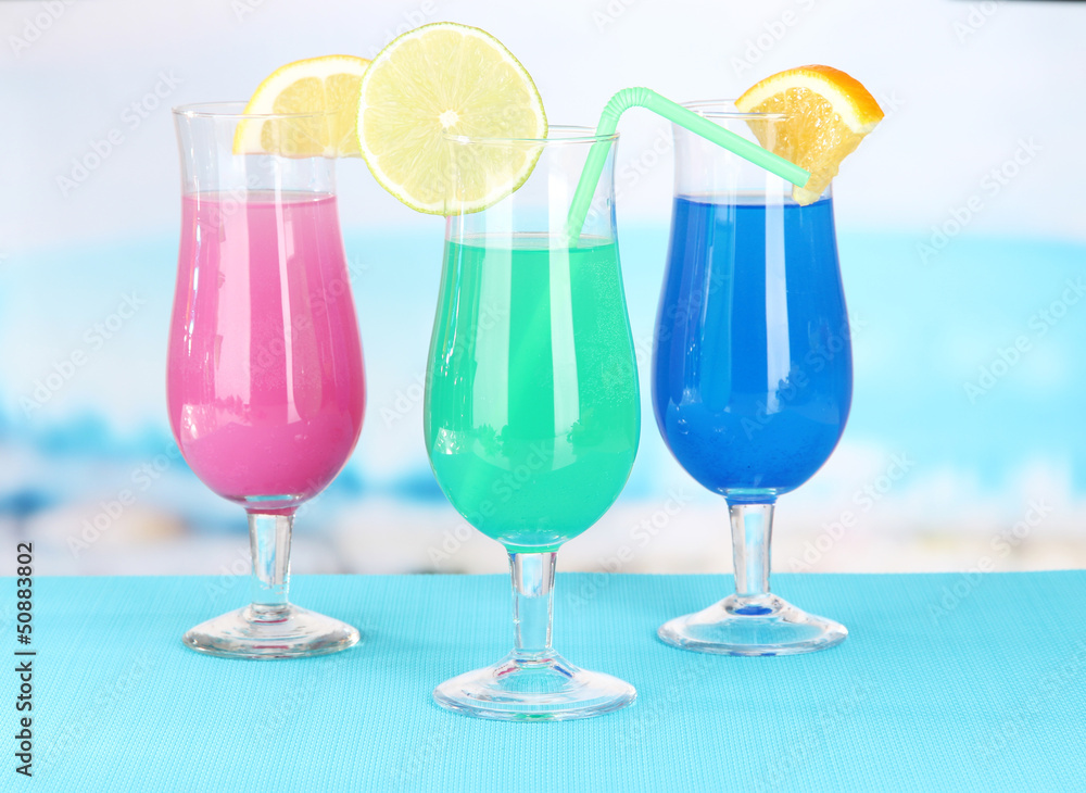 Glasses of cocktails on table near pool