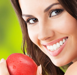 Young woman with red apple, outdoors