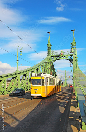 Board z aluminiowym obramowaniem Pomarańczowy tramwaj na moście wolności w Budapeszcie, Węgry