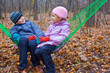 © Pavel Losevsky - Brother and sister sitting together in hammock in autumn forest