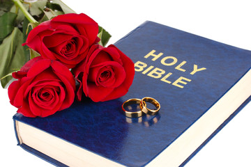 Wall Mural - Wedding rings with roses on bible isolated on white